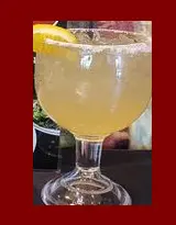 A glass of lemonade with lemon on the side.