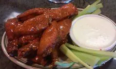A plate of chicken wings with ranch and celery.