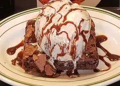 A plate of ice cream and brownie on top of a table.